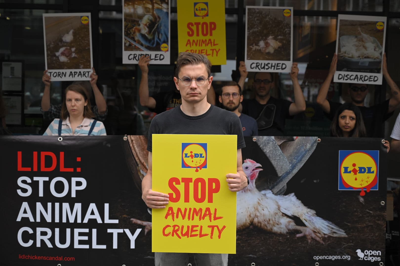 Anima volunteer Tomasz Herok holding a 'Stop Animal Cruelty' sign during a protest against Lidl to stop the sale of fast-growing chickens bred to suffer.