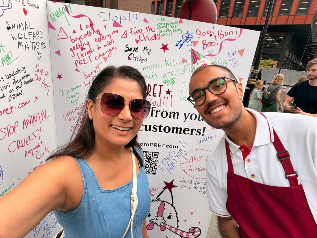 Goldy taking a selfie at a Pret protest next to a message board with supporter pledges