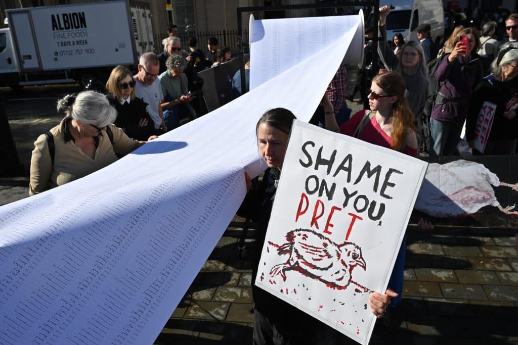 Volunteers display petition scroll and SHAME ON YOU PRET sign